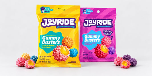 Original and Berry JOYRIDE Gummy Busters with loose candy on a plain pale-grey studio backdrop